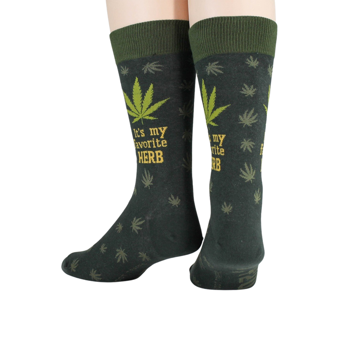 A pair of dark green socks with a marijuana leaf pattern and the words 