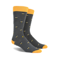 A pair of charcoal gray crew socks with a repeating pattern of yellow bees and honeycombs. Yellow tops.