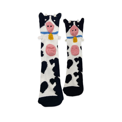 Black and white spotted socks with a cow face at the top, featuring a 3D pink snout, sticking-out ears, and a yellow bell.