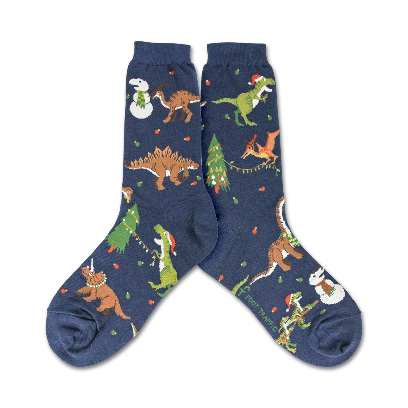 A pair of navy blue crew socks showcasing a whimsical Christmas design. The socks feature various dinosaurs wearing Santa hats and celebrating around decorated Christmas trees and snowmen.