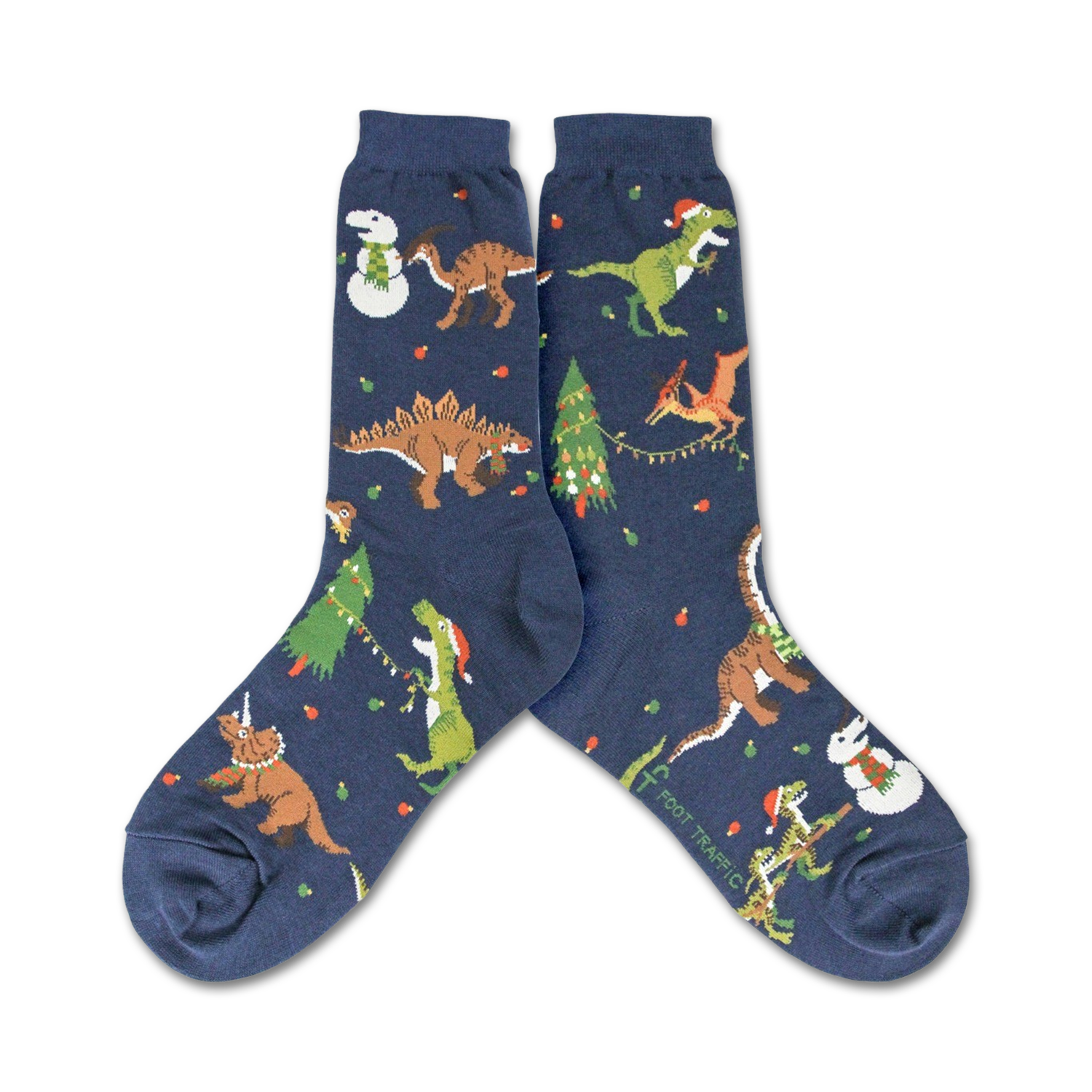 A pair of navy blue crew socks showcasing a whimsical Christmas design. The socks feature various dinosaurs wearing Santa hats and celebrating around decorated Christmas trees and snowmen.