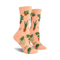 A pair of peach-colored crew socks with a fun pattern of potted plants and plant puns like 'Never leaf me'.