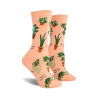 A pair of peach-colored crew socks with a fun pattern of potted plants and plant puns like 'Never leaf me'.