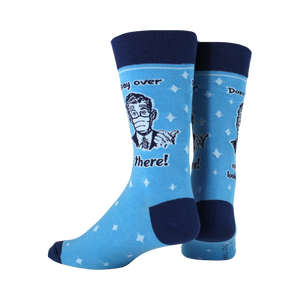 A pair of blue socks with white stars and a man in a suit wearing a mask on them. The text on the socks says 