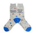 A pair of gray crew socks with blue cuffs.  The socks are decorated with colorful illustrations of crafting tools and the text 'Craftiness is Happiness' and 'Crafters Gonna Craft'.