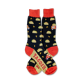 A pair of crew socks with a black background, orange cuffs, and a fun design of tacos and a taco truck. 