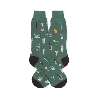 Green crew socks patterned with small bar tools, mixed drinks, and the text cocktail snob. Features dark heels and toes.