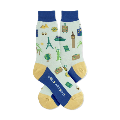 Pair of light blue crew socks with a travel theme. Features landmarks, suitcases, and a compass in navy and gold.