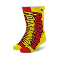 A pair of crew socks in red and yellow, featuring a stylized "Hulkamania" logo. The socks have black soles.