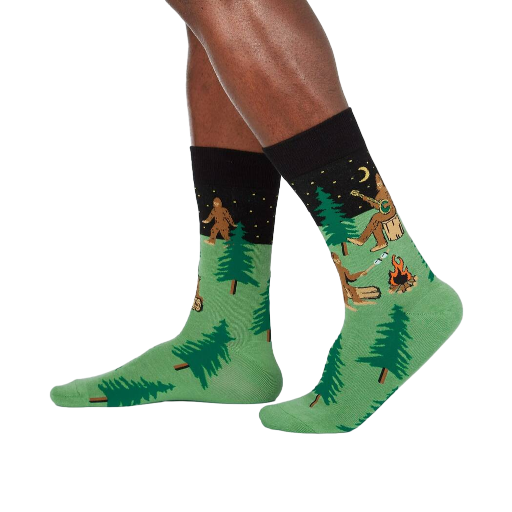 Lifestyle shot showing Sasquatch Camp Out socks on a person's legs, showcasing the design from a slightly different angle.