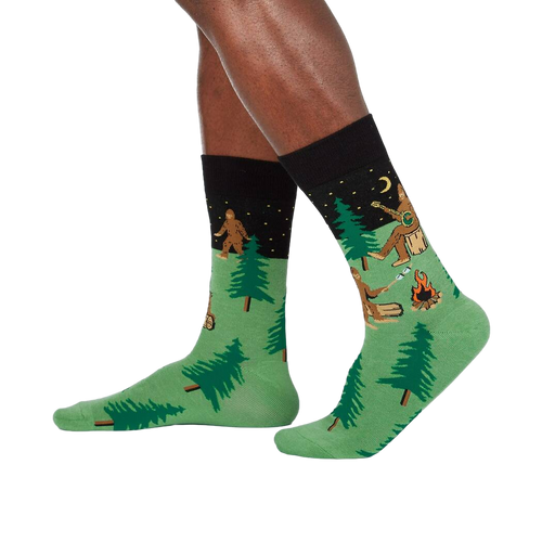 Lifestyle shot showing Sasquatch Camp Out socks on a person's legs, showcasing the design from a slightly different angle.