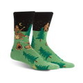 Pair of green and black crew socks featuring a whimsical Sasquatch playing banjo around a campfire in the woods.