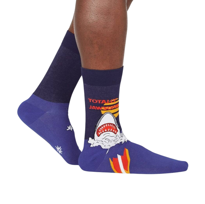 A pair of blue socks with a shark graphic on the left sock and the words 