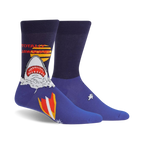 Pair of navy blue crew socks featuring a graphic of a shark emerging from water with a retro surfboard design and 'Totally Jawsome!' text.