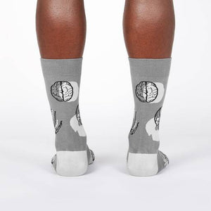 A pair of gray socks with a pattern of brains, hands, and skulls.