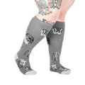 Lifestyle shot showing a model wearing the anatomical knee-high socks.  The socks are gray with skulls, ribcages, and hearts.