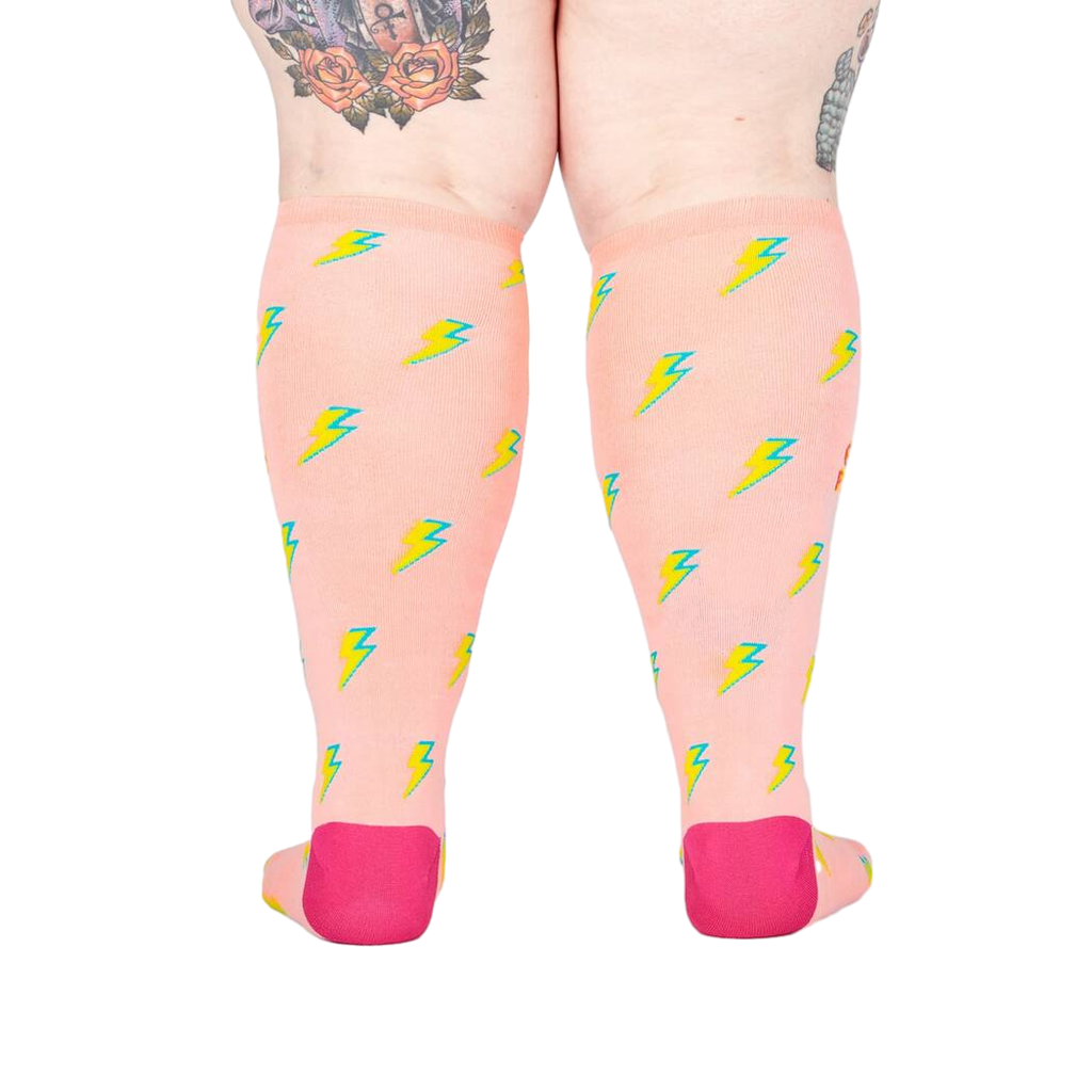 Back view of the 'GRL PWR' knee-high socks, highlighting the full lightning bolt pattern on a peachy pink background.