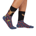 Lifestyle shot of a person's legs wearing the 'All Bundled Up' socks. The socks feature a moose wearing a scarf and snowflake pattern.