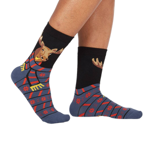 Lifestyle shot of a person's legs wearing the 'All Bundled Up' socks. The socks feature a moose wearing a scarf and snowflake pattern.