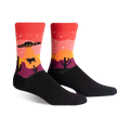 Crew socks in black, red, orange, and purple, featuring a desert sunset scene with a UFO, stars, cacti, and a cow.