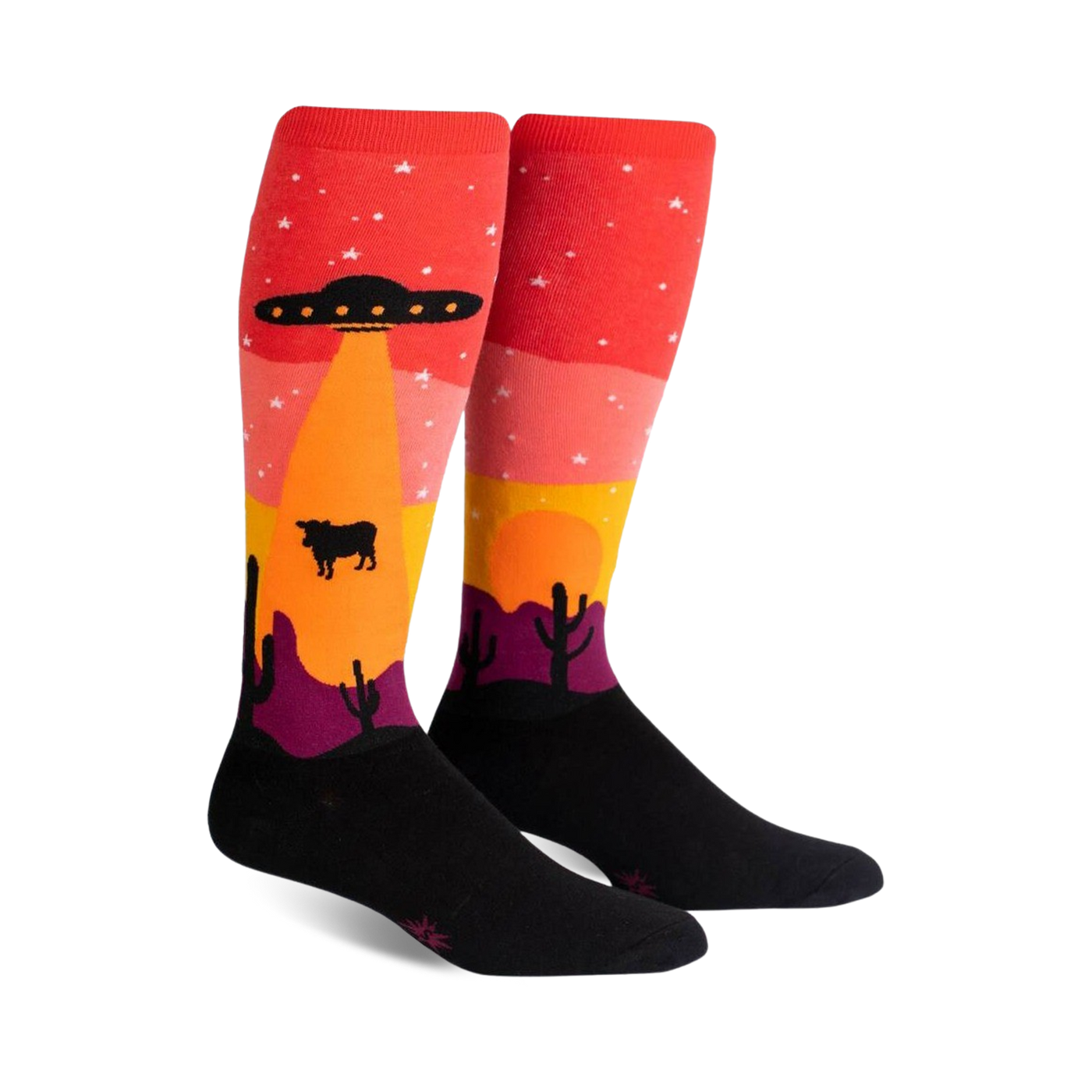 Pair of knee-high socks; red, orange, yellow, purple, and black. Design features an alien spaceship abducting a cow in a desert landscape at sunset.