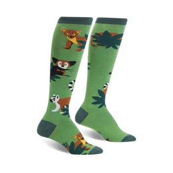 A pair of green knee-high socks with illustrated lemurs, fossa, and tropical leaves. Brown, white, and dark-green details on a bright green background.
