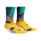 Pair of crew socks in teal, mustard yellow, and brown. Design features a skeleton pirate at the helm of a ship with treasure.