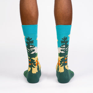 A pair of blue and green socks with a pattern of pine trees on them.