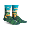 Pair of crew socks showcasing a nature scene. Teal, green, and orange colors depict trees, a lake, and sky. Fun, artistic design.