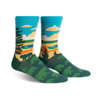 Pair of crew socks showcasing a nature scene. Teal, green, and orange colors depict trees, a lake, and sky. Fun, artistic design.