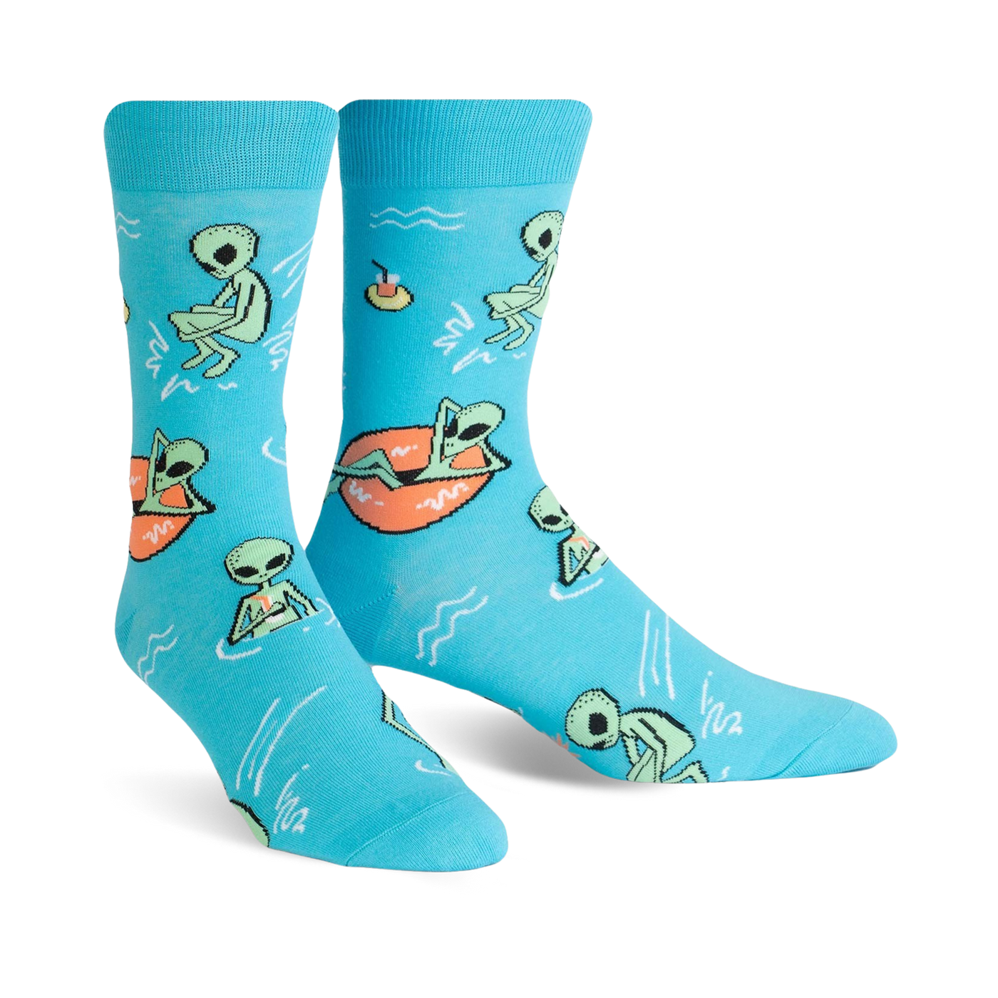 A pair of turquoise crew socks featuring a fun pattern of green aliens relaxing in the water, some on inner tubes. 