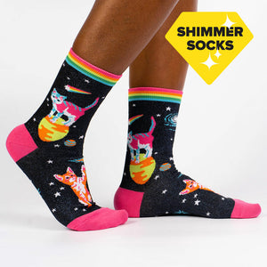A pair of black socks with a colorful pattern of cats in space. The socks have a pink toe and heel, and a rainbow stripe at the top.