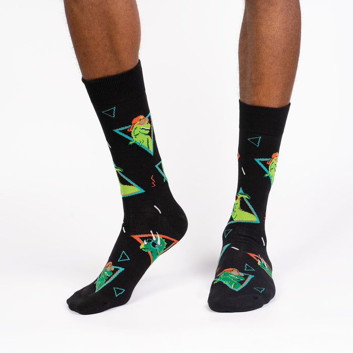 A pair of black socks with a pattern of green dinosaurs wearing sunglasses.