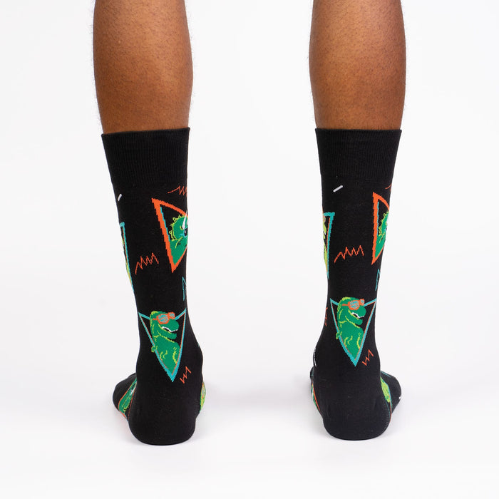 A pair of black socks with a pattern of green dinosaurs wearing sunglasses.