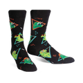 Pair of black crew socks with green dinosaurs wearing sunglasses, set against a 90s-style geometric pattern. 