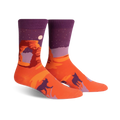 Crew socks in orange and purple, showcasing Delicate Arch at sunset under a starry night sky.  Silhouetted figures of coyotes or dogs are also featured.