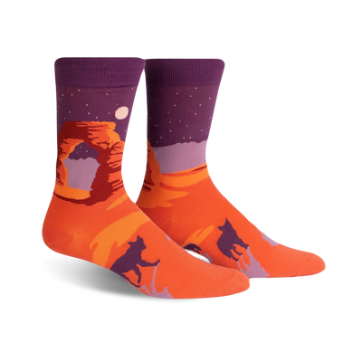 orange crew socks with purple cuff feature a desert scene with a large red rock formation, a moon, and two howling coyotes.   