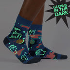 Lifestyle shot showing the 'You Glow Girl' socks on a model's legs. The socks are glowing in the dark, highlighting the design details.