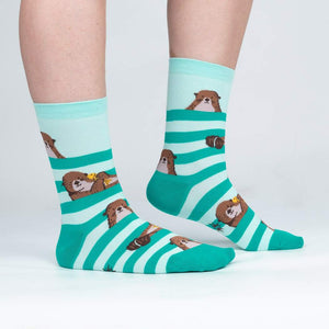 A pair of mint green socks with a pattern of otters peeking over a striped background in darker green.