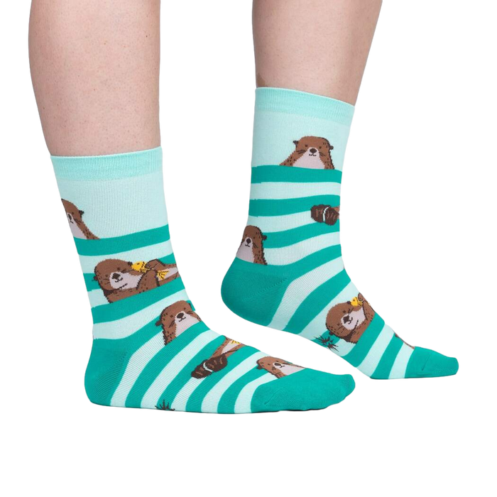 Lifestyle shot of a person wearing the teal and mint otter socks. Shows the fit and look on feet.