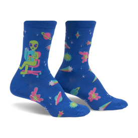 front view of a pair of blue socks with an alien reading a book in a chair, stars, planets and comets in pink, green, yellow and white.