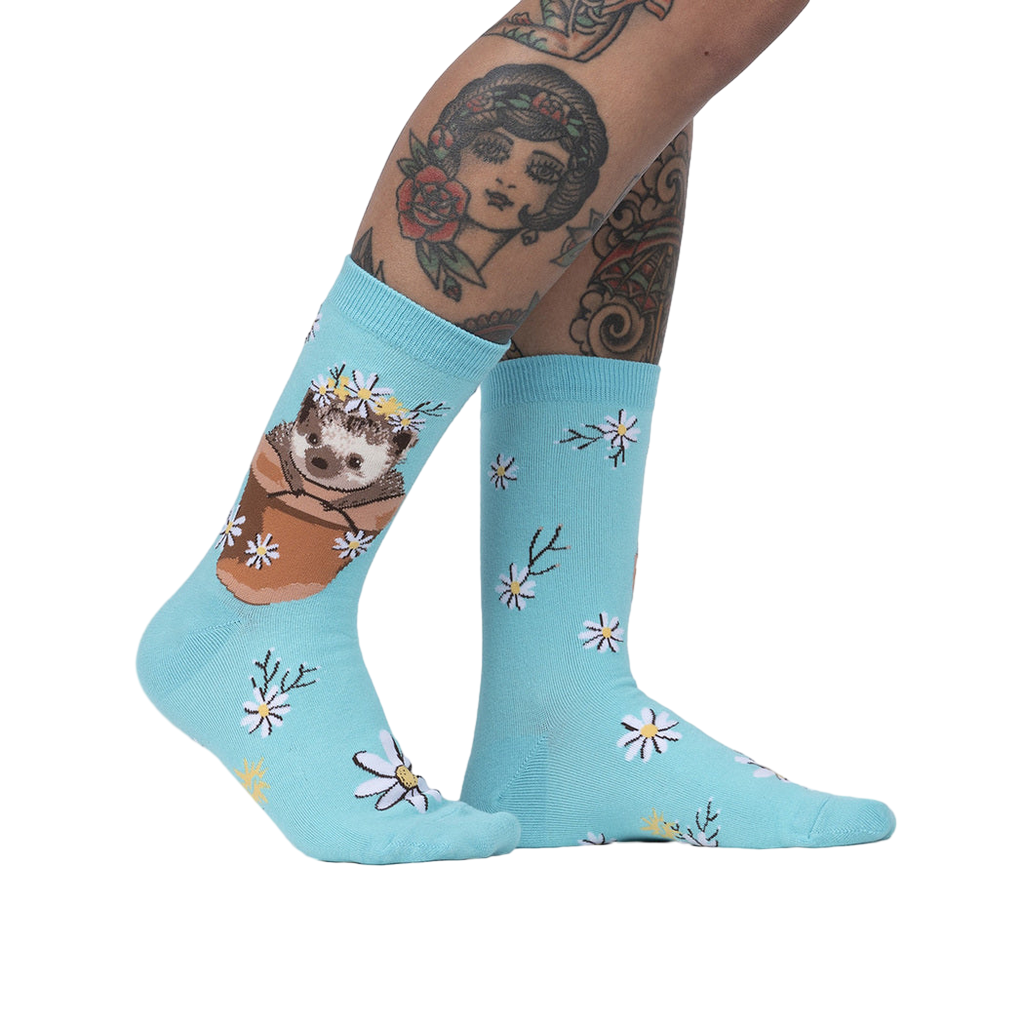 Lifestyle shot of a person's legs wearing the 'My Dear Hedgehog' socks, showcasing the socks on a model with tattoos.