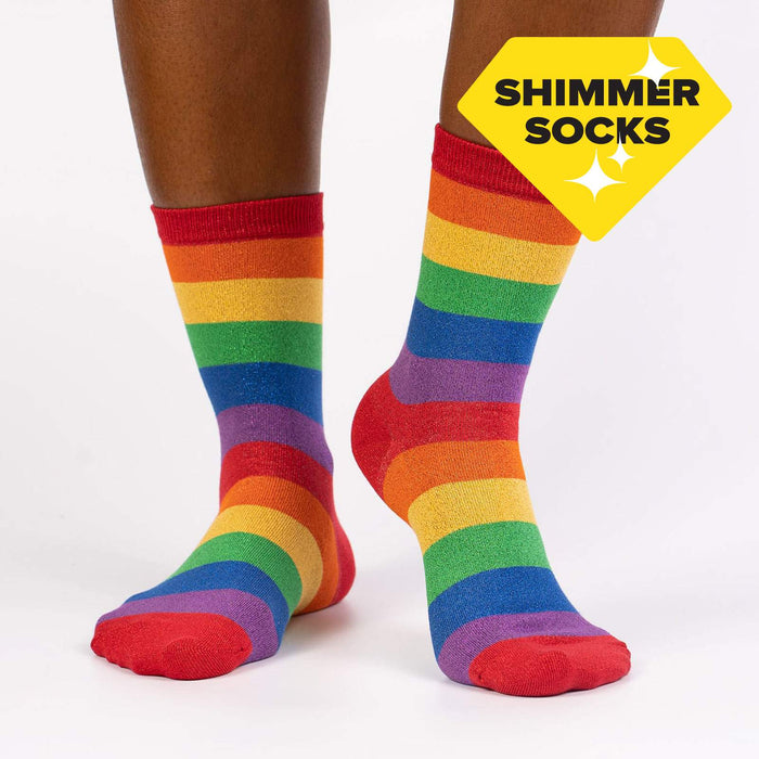 An image of a person's legs from the back. The person is wearing red socks with rainbow stripes.