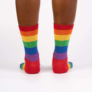 An image of a person's legs from the back. The person is wearing red socks with rainbow stripes.