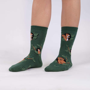 A pair of green socks with a pattern of foxes, raccoons, and owls.