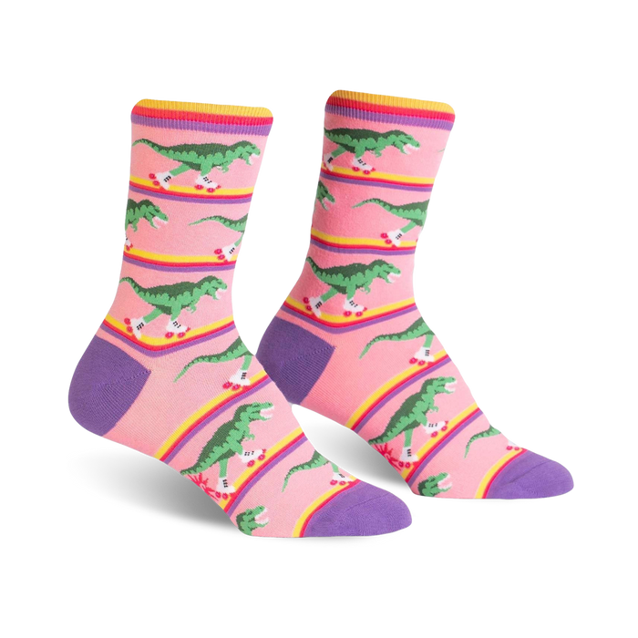 pink womens crew socks with a design of green roller-skating dinosaurs on a rainbow-colored stripe.  