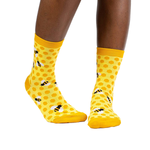Lifestyle shot of a model wearing the yellow honeycomb bee socks.