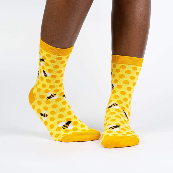 A pair of yellow socks with a honeycomb pattern and black and white bee accents.