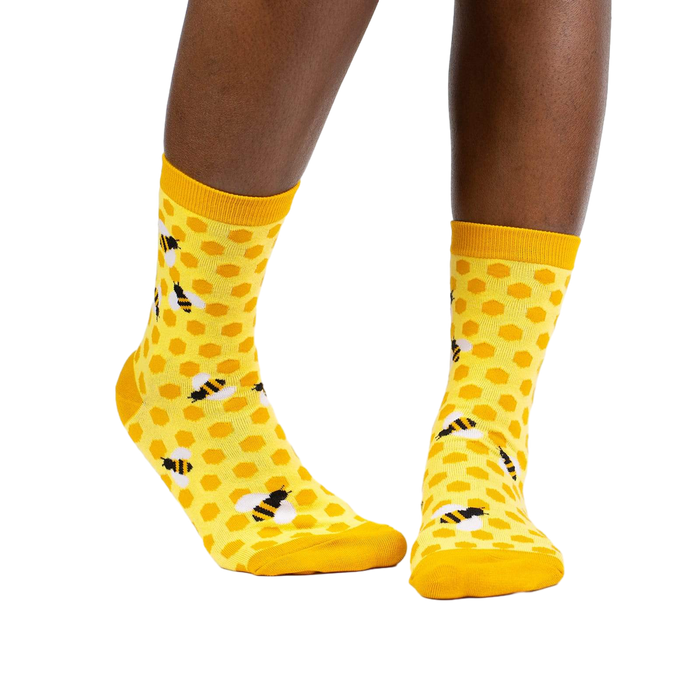 Lifestyle shot of a model wearing the yellow honeycomb bee socks.