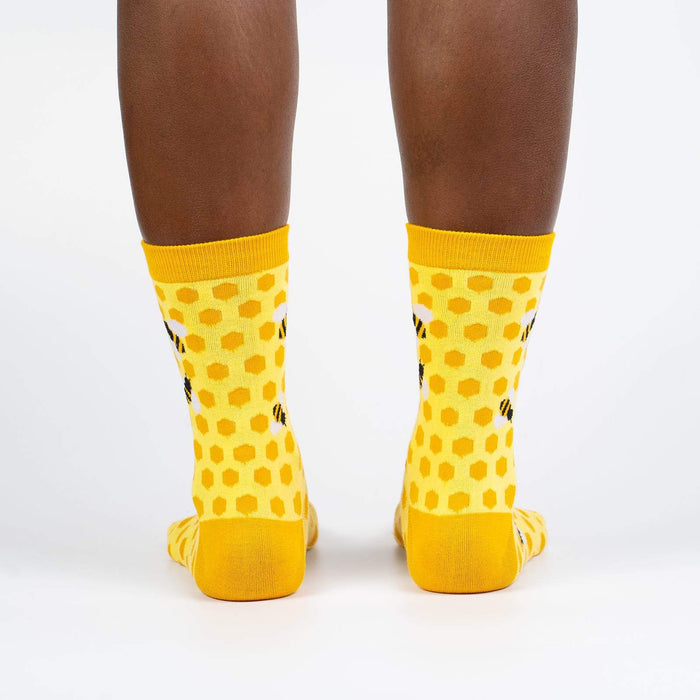 A pair of yellow socks with a honeycomb pattern and black and white bee accents.